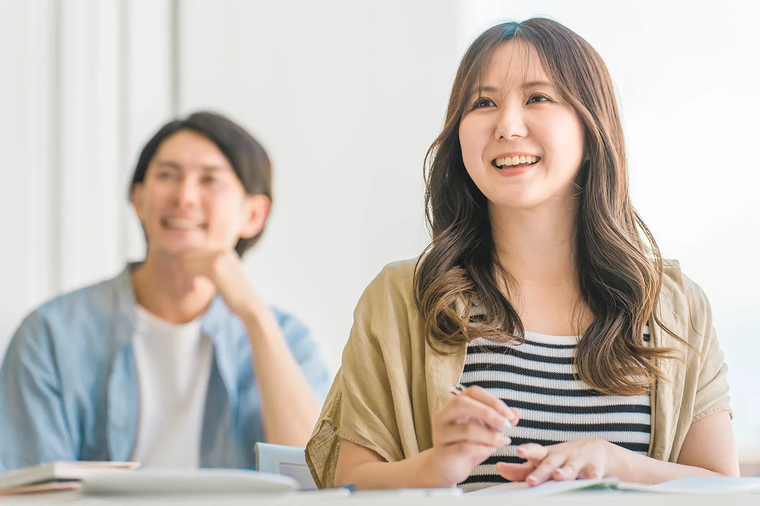 ノートをとりながら講義を聞く女性と男性の写真