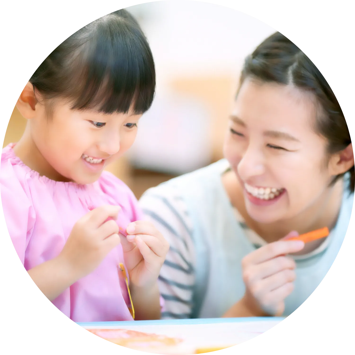 クレヨンを持つ女の子とエプロンの女性の写真