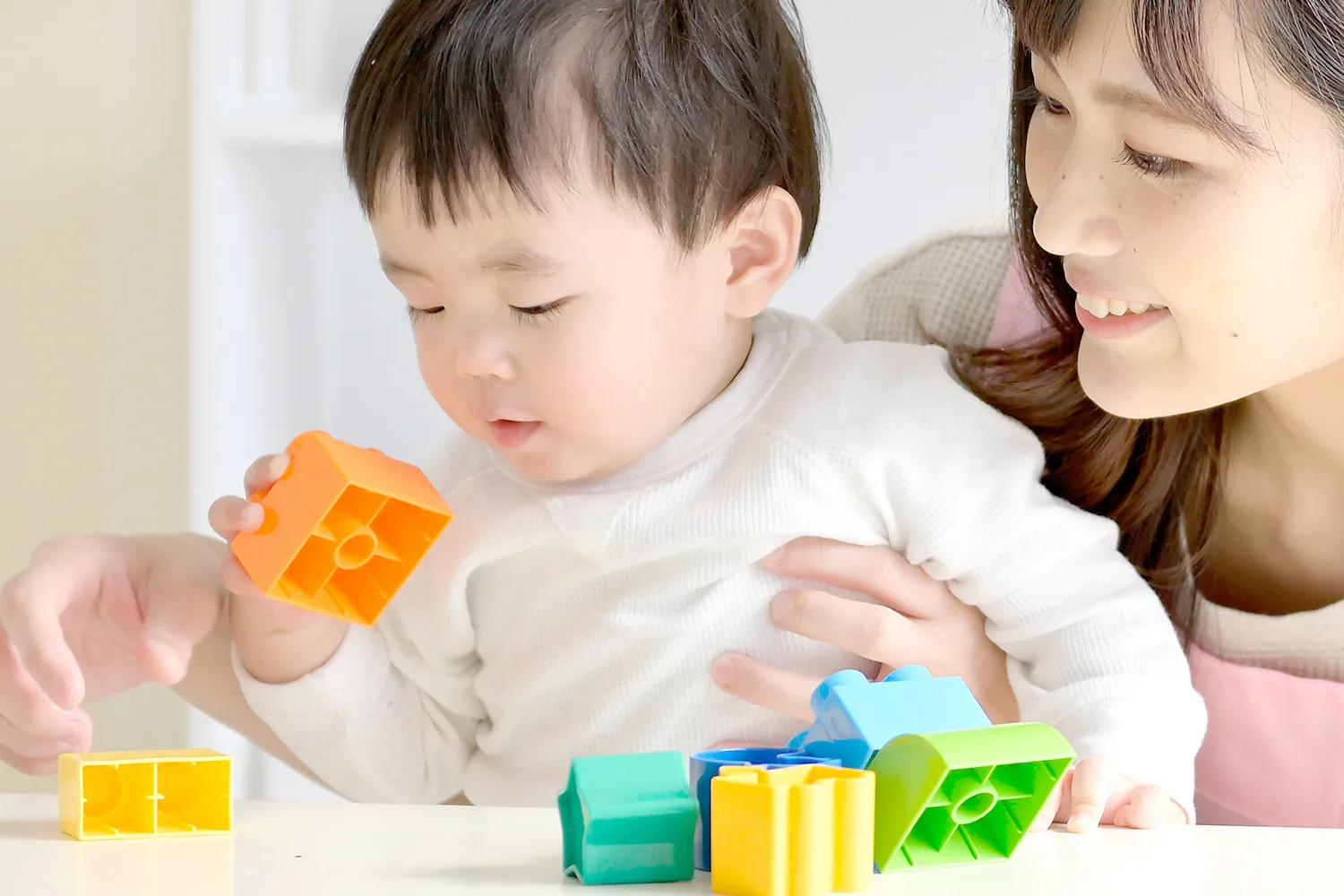 ブロックで遊ぶ子供と指導する先生の写真