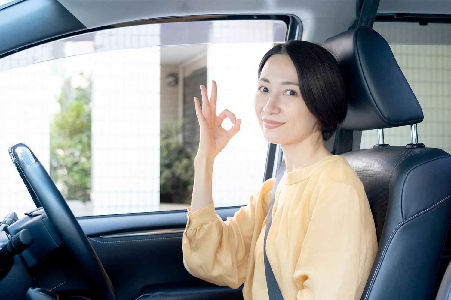 車の運転席でOKのサインをする女性の写真