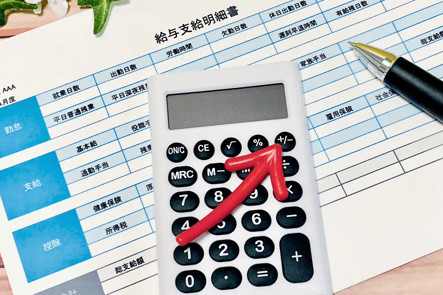給与明細と電卓、上向きの矢印の画像