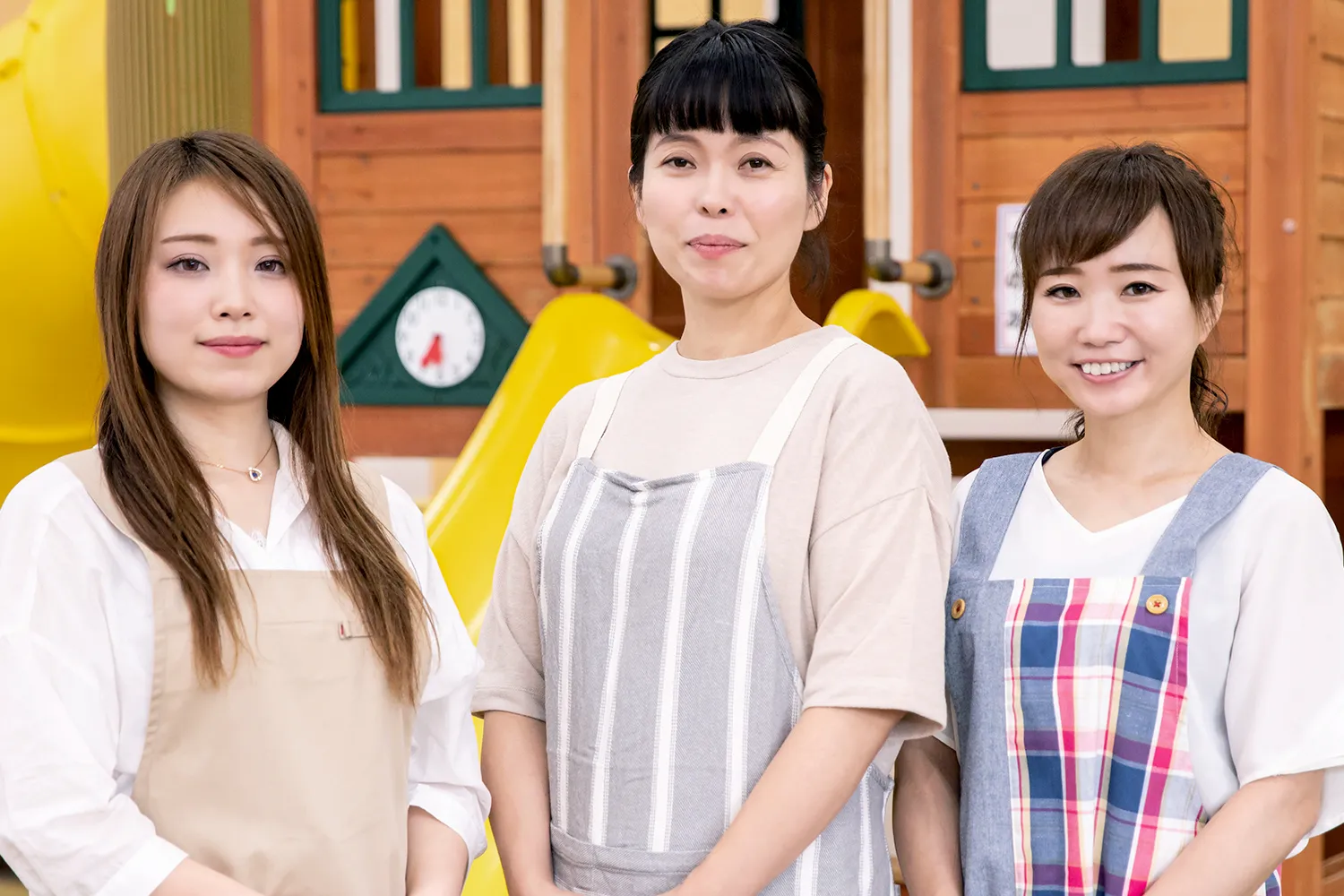 私服にエプロン姿の保育士三人の写真