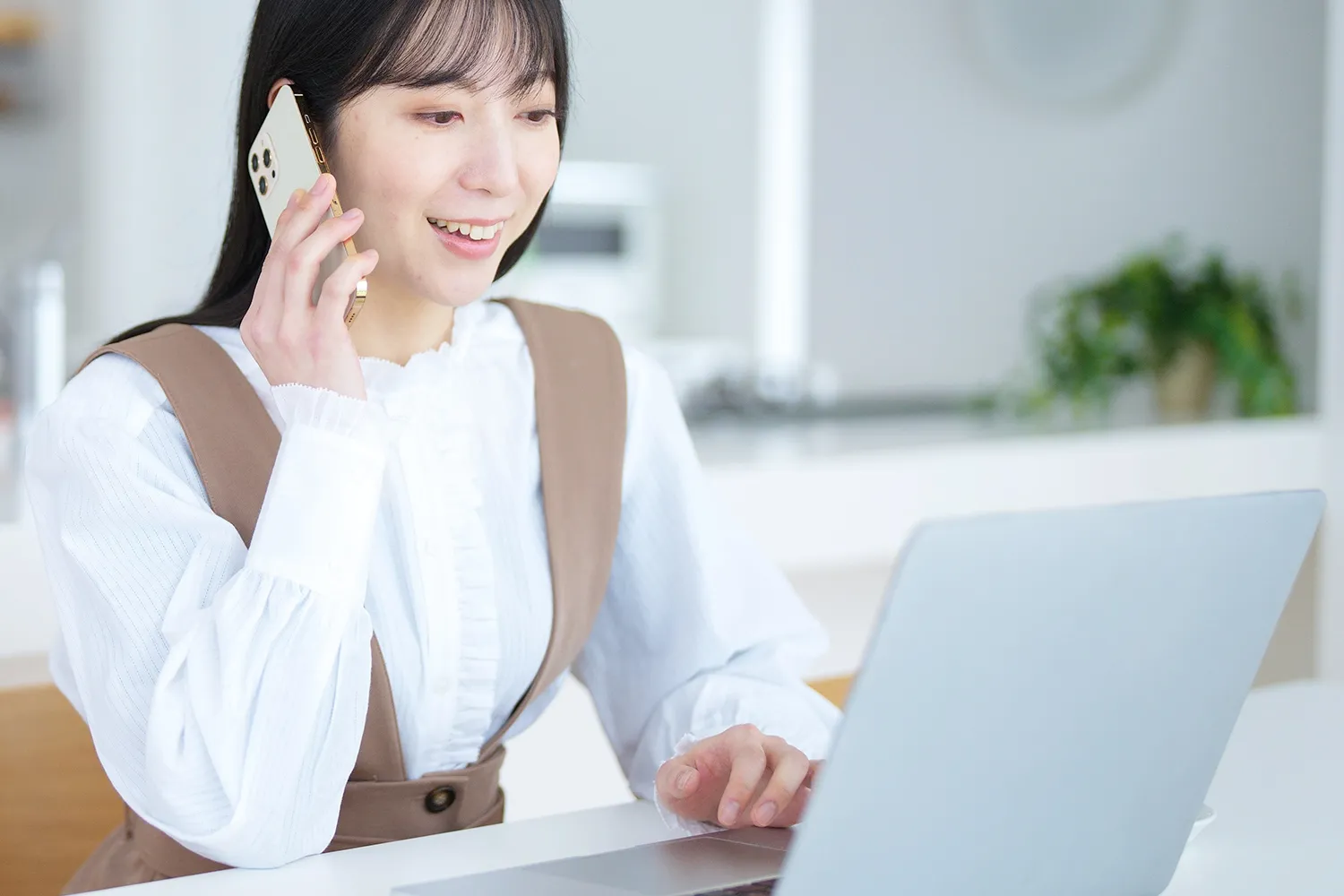 パソコンを見ながら電話する若い女性の奢侈な