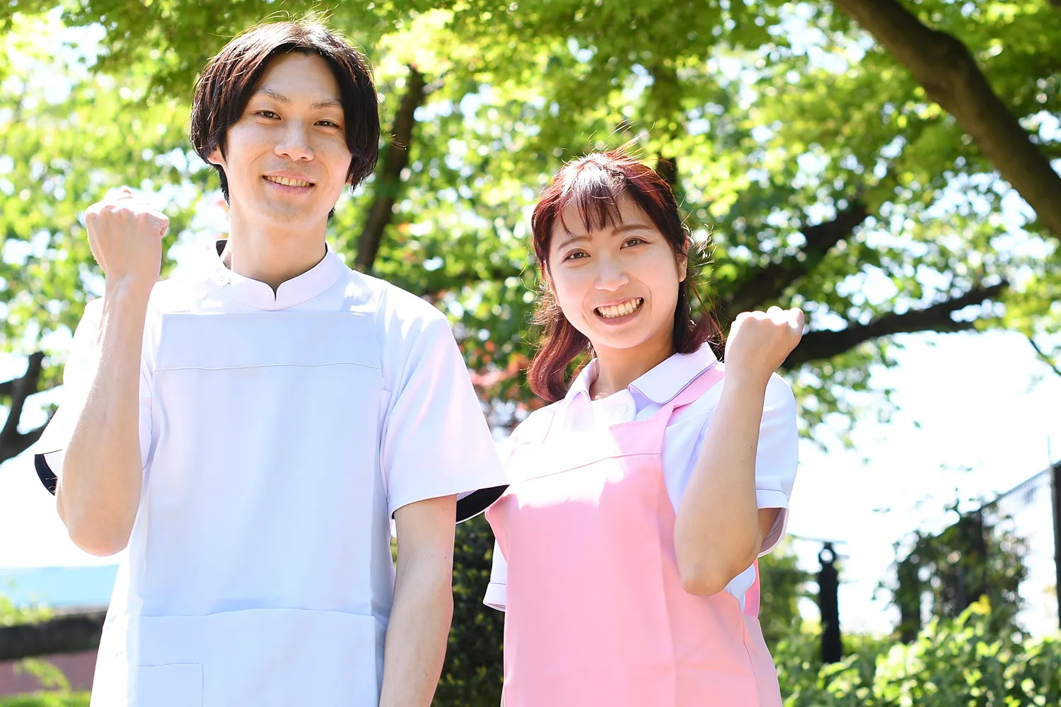 若葉をバックにエプロンをつけてガッツポーズする男女の写真